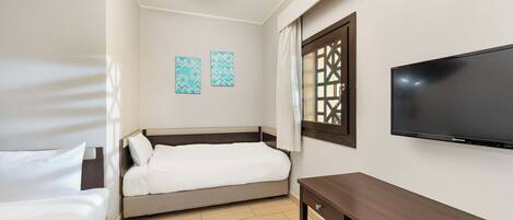 Una habitación de hotel con una cama, un televisor, un banco y dos obras de arte colgadas en la pared.