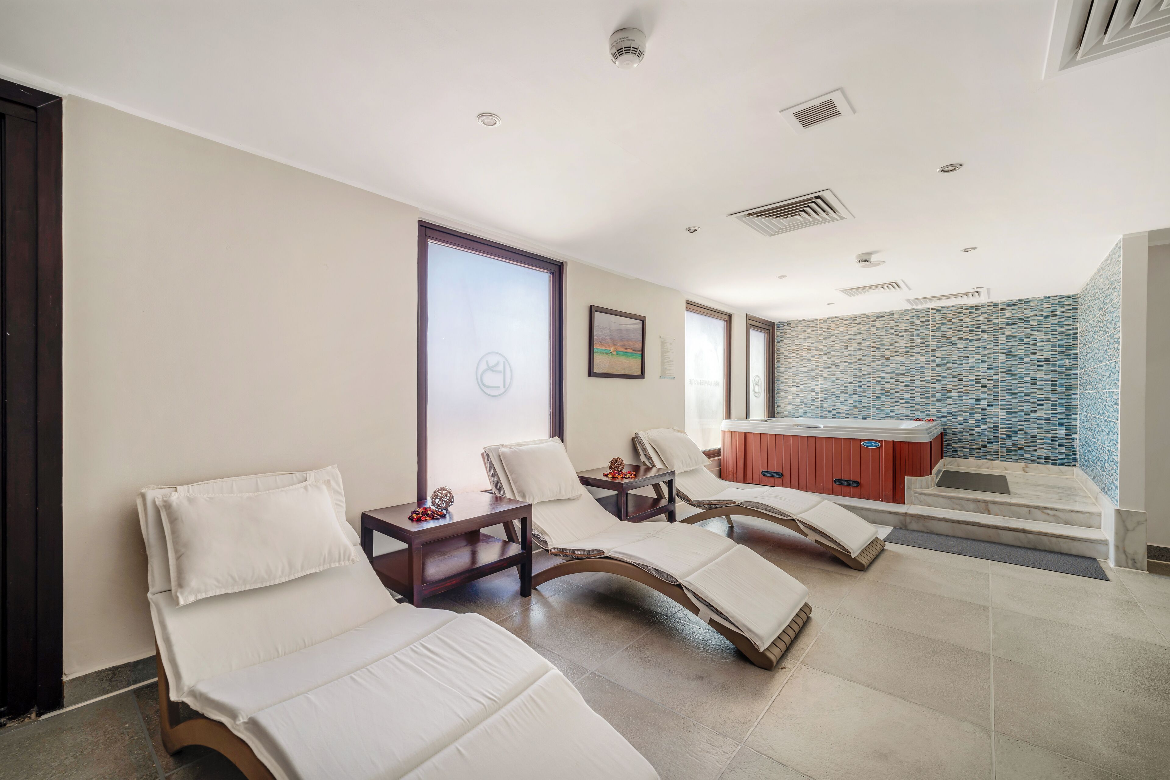 Une salle de spa moderne équipée de deux fauteuils inclinables, d’une table de massage et d’un bain à remous.