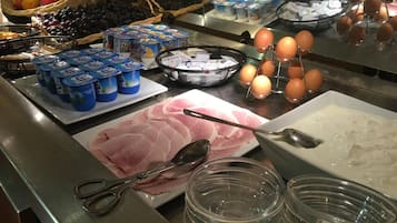 Een buffet met diverse etenswaren, waaronder yoghurt, eieren en vleesschotel.