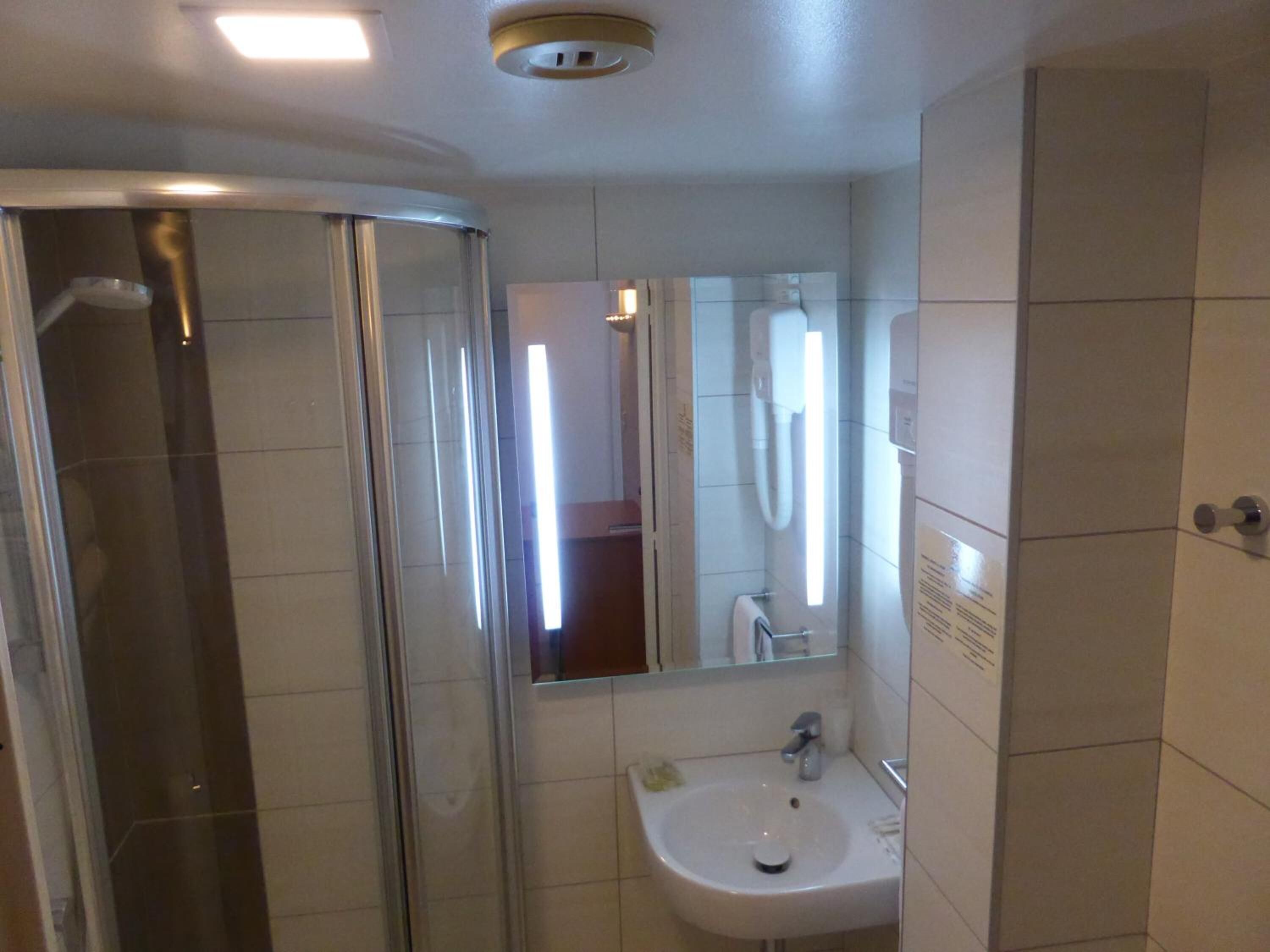 Une salle de bain avec une douche à parois de verre, un lavabo et un miroir.
