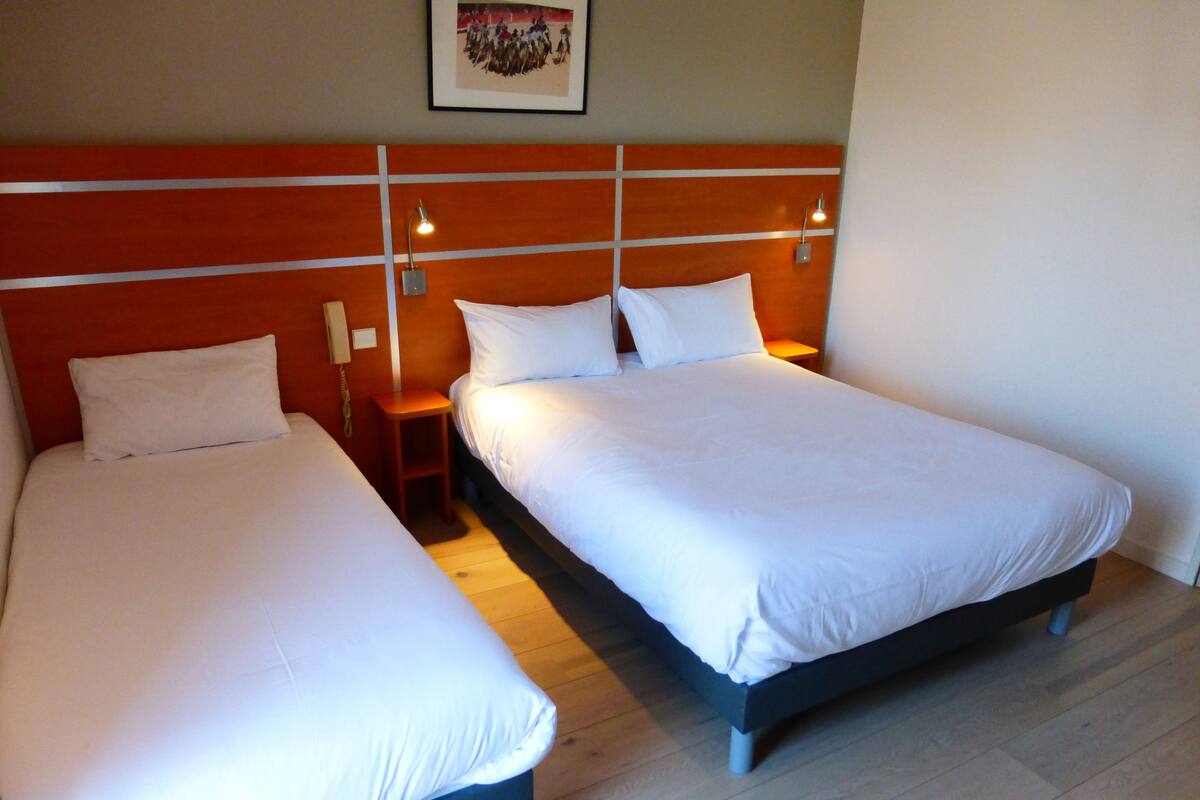 Two single beds with white linens, wooden headboards, and bedside tables with lamps.
