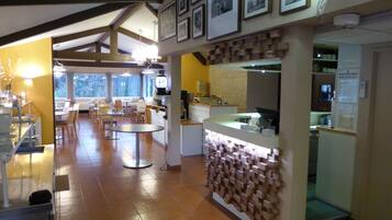 A restaurant with a modern interior, featuring wooden beams, a brick wall, and a counter with a digital clock.