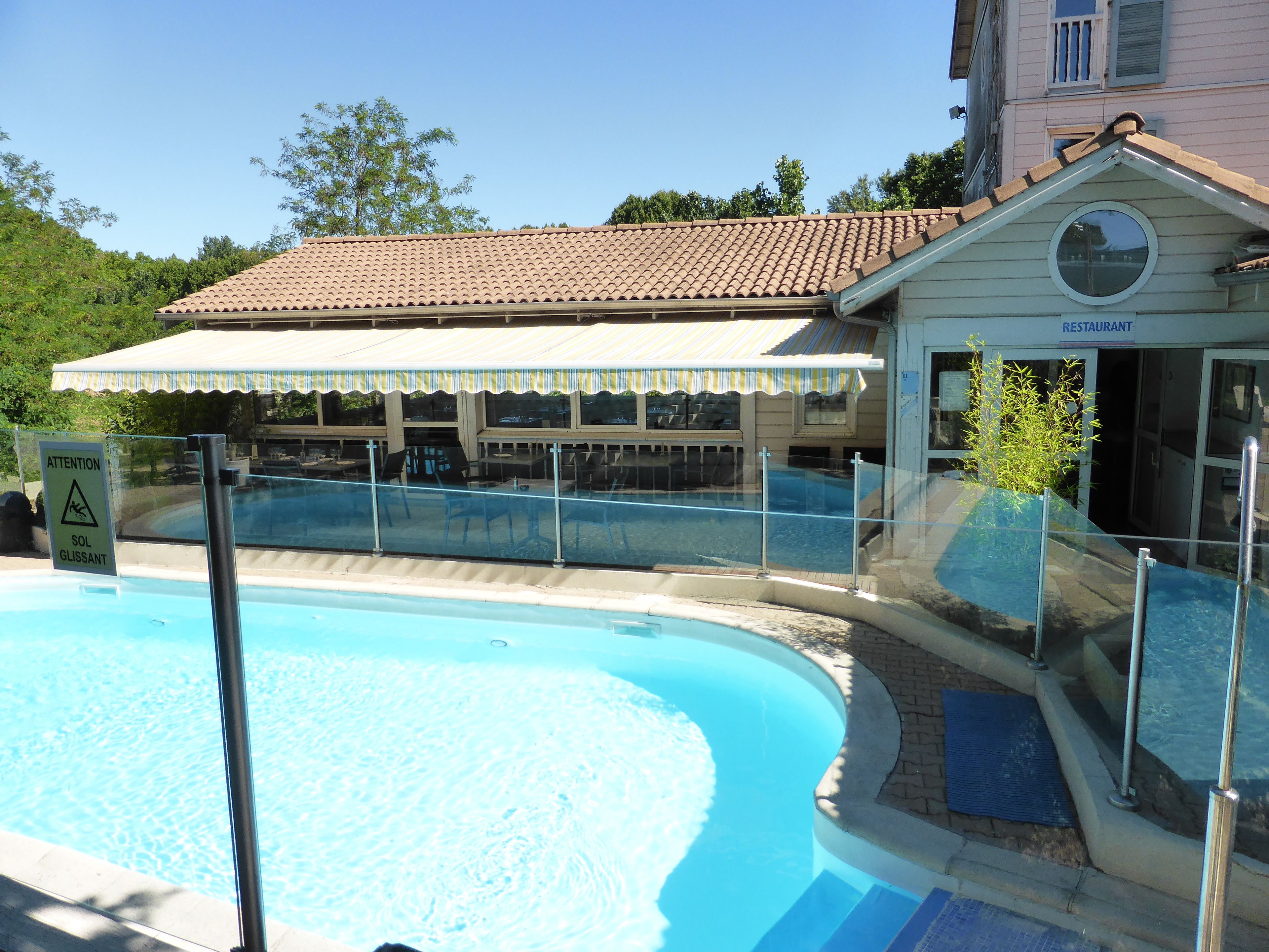 A swimming pool with a glass barrier, a covered seating area, and a building labeled 'RESTAURANT'.