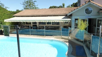 A swimming pool with a glass barrier, a covered seating area, and a building labeled 'RESTAURANT'.