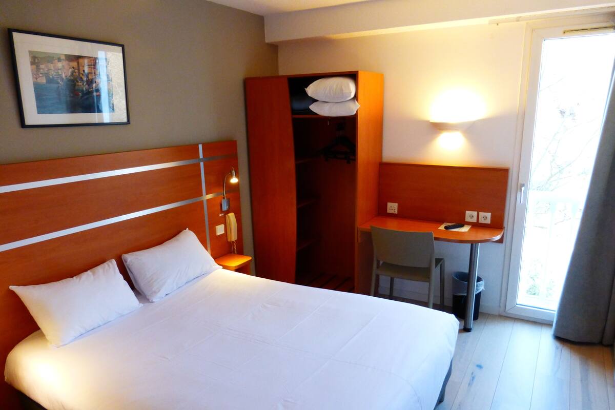 A hotel room with a bed, a desk, and a chair.