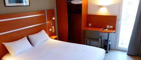 Una habitación de hotel con una cama, un escritorio y una silla.