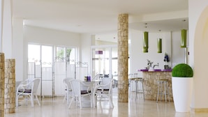 Un amplio comedor con sillas de mimbre blanco y un pilar de piedra.