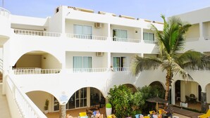 Un hotel de varios pisos con balcones, zonas de estar al aire libre y una palmera.