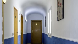 A hallway with wooden flooring, white and blue walls, and a wooden door at the end. - Piccolo Hotel (Florence)
