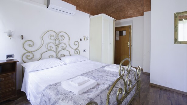 A bedroom with a bed, a nightstand, a wardrobe, and a door. - Piccolo Hotel (Florence)