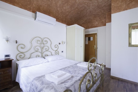 A bedroom with a bed, a nightstand, a wardrobe, and a door.