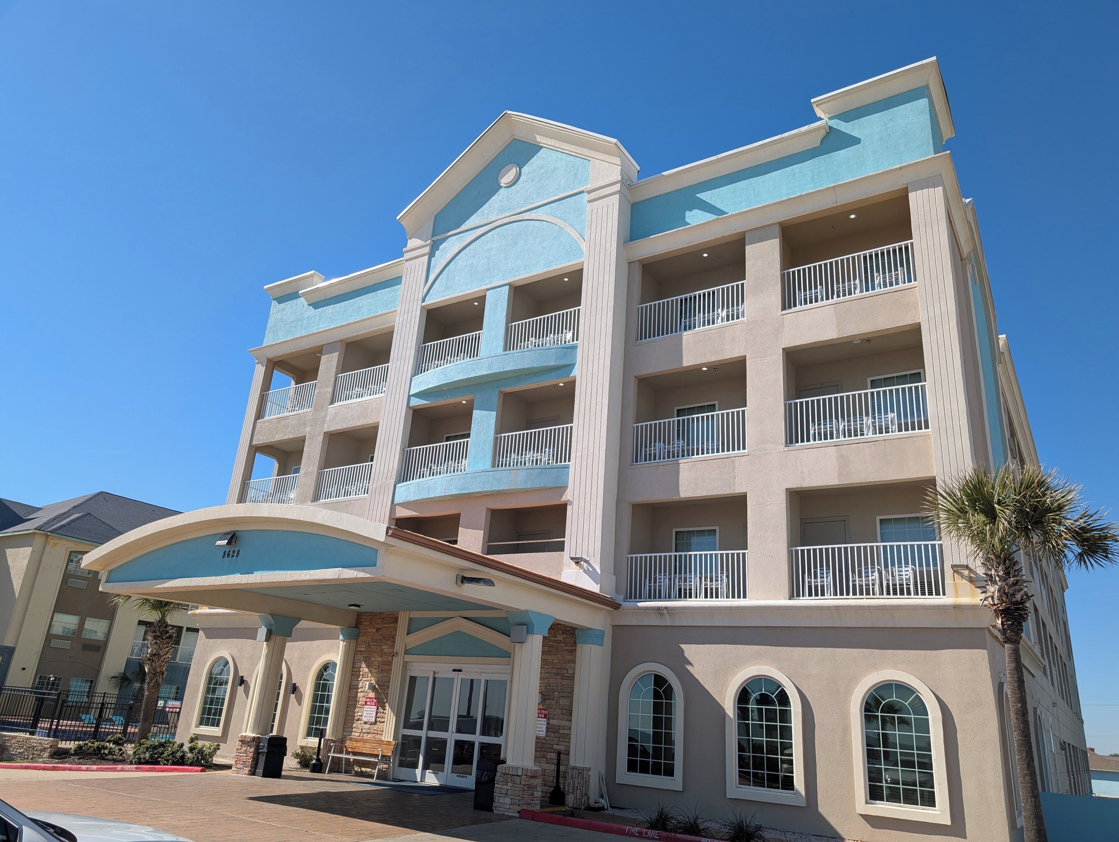 Un hotel de varios pisos con un atrio central, balcones y fachada de piedra.