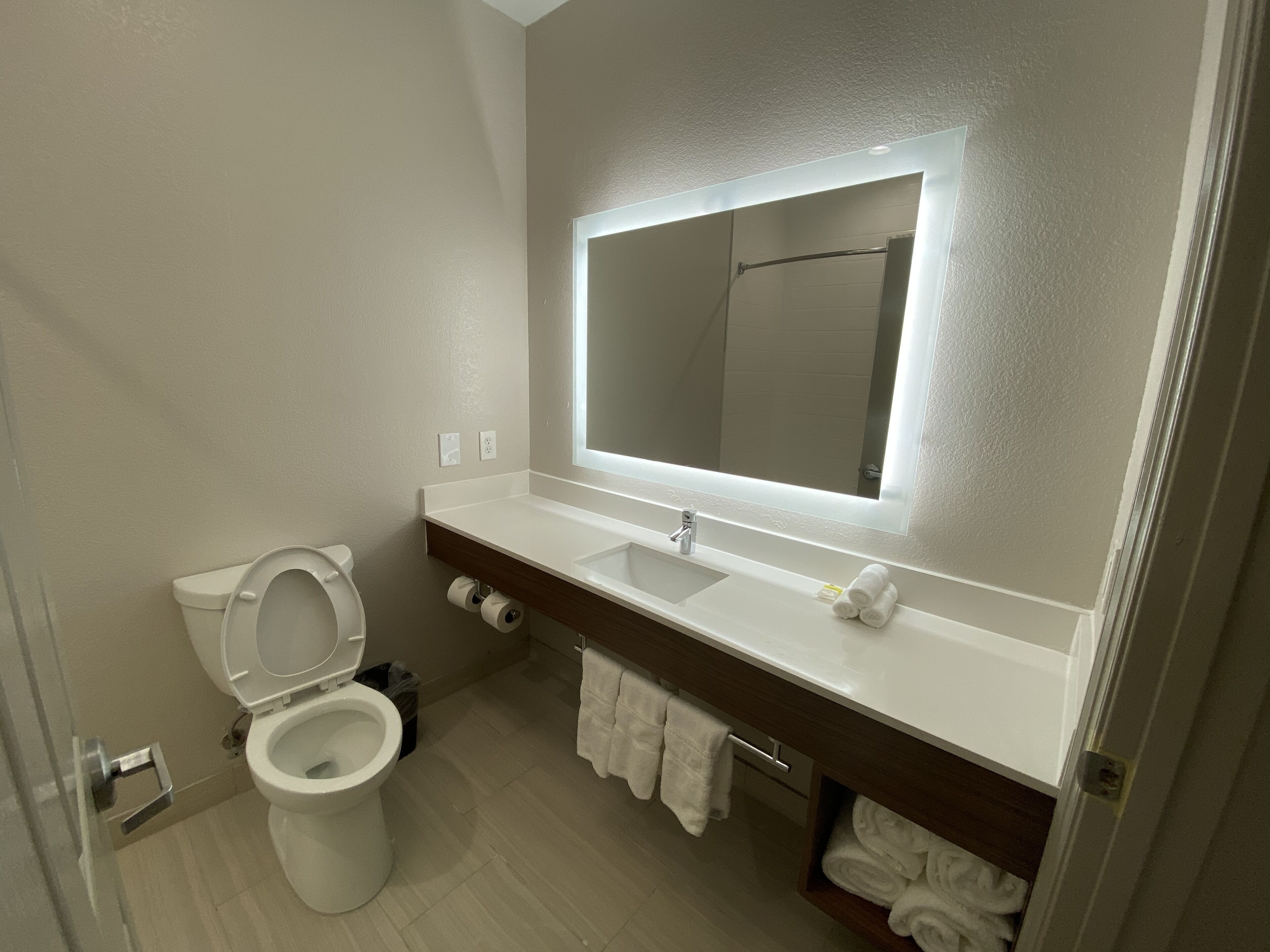 A modern bathroom with a toilet, sink, and mirror.