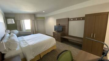 Una habitación de hotel con cama, escritorio, televisor y armario.