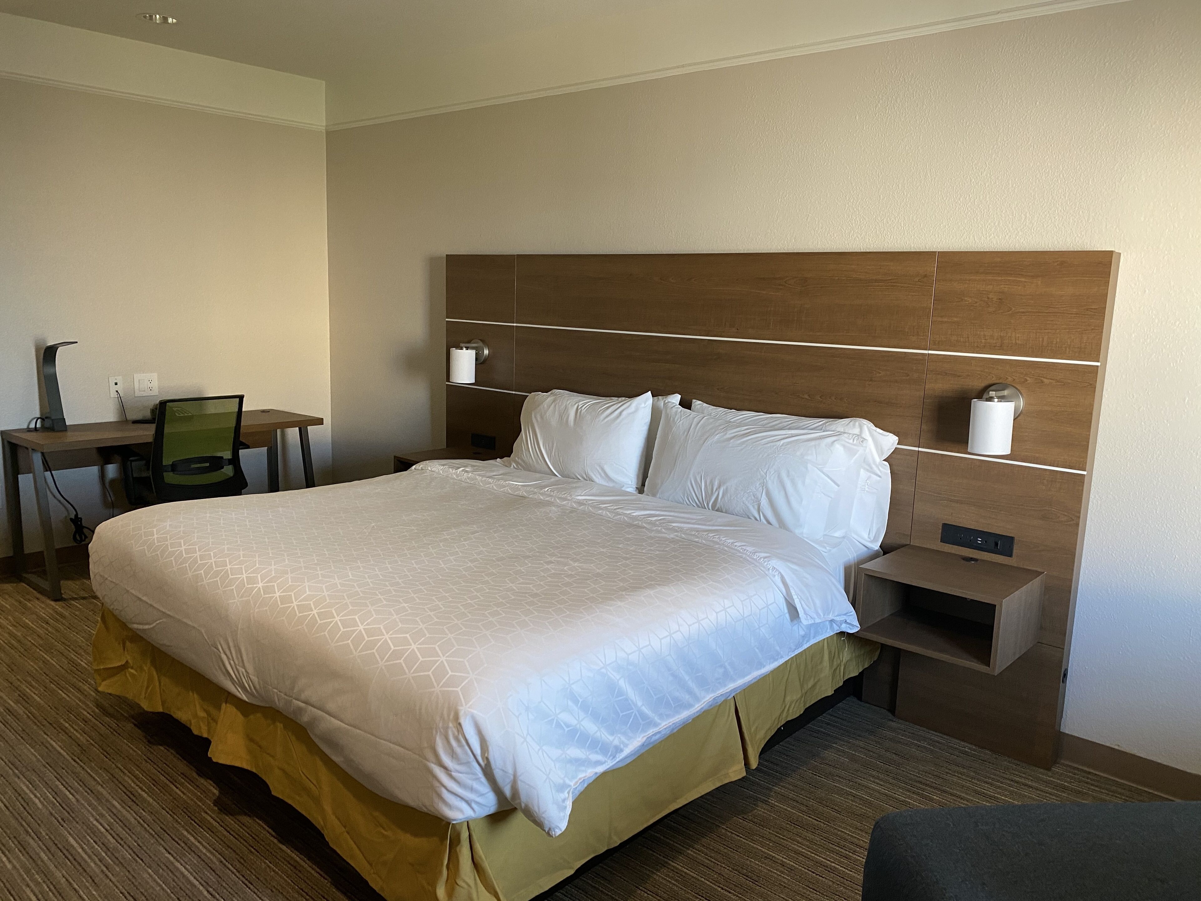 Een hotelkamer met een groot bed, een bureau en een stoel.