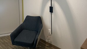 Una habitación con una sola silla, una lámpara de pared y una puerta.