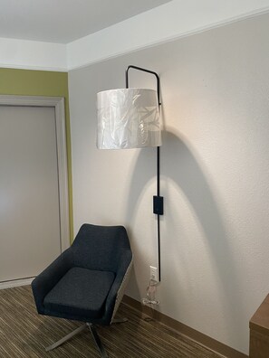 Una habitación con una sola silla, una lámpara de pared y una puerta.