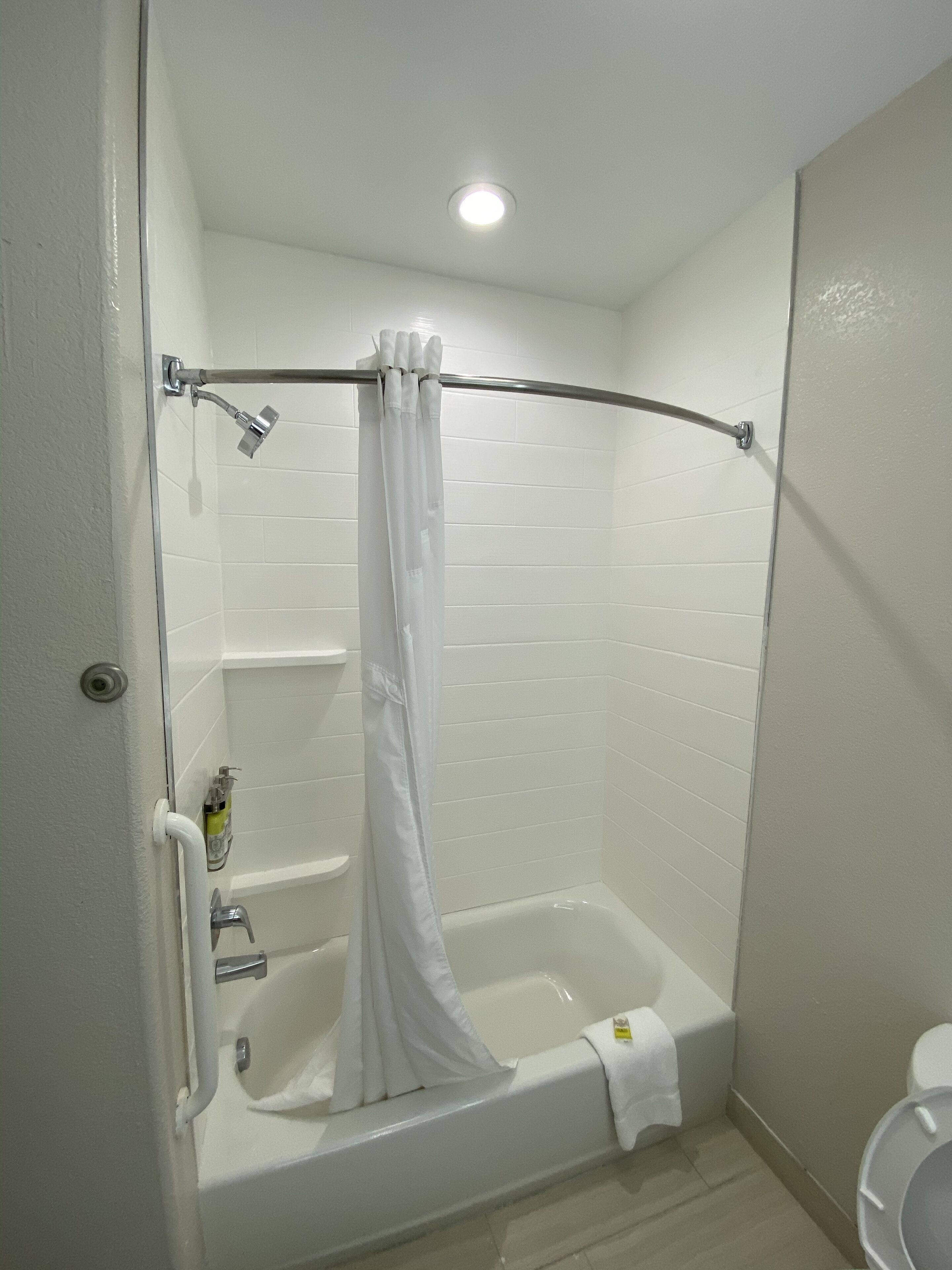 A small, white bathroom with a shower, a toilet, and a bathtub.