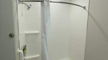 A small, white bathroom with a shower, a toilet, and a bathtub.