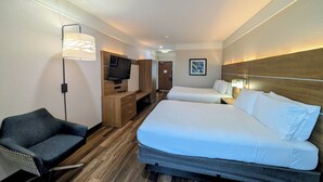 Una habitación de hotel con cama, televisor, escritorio y silla.