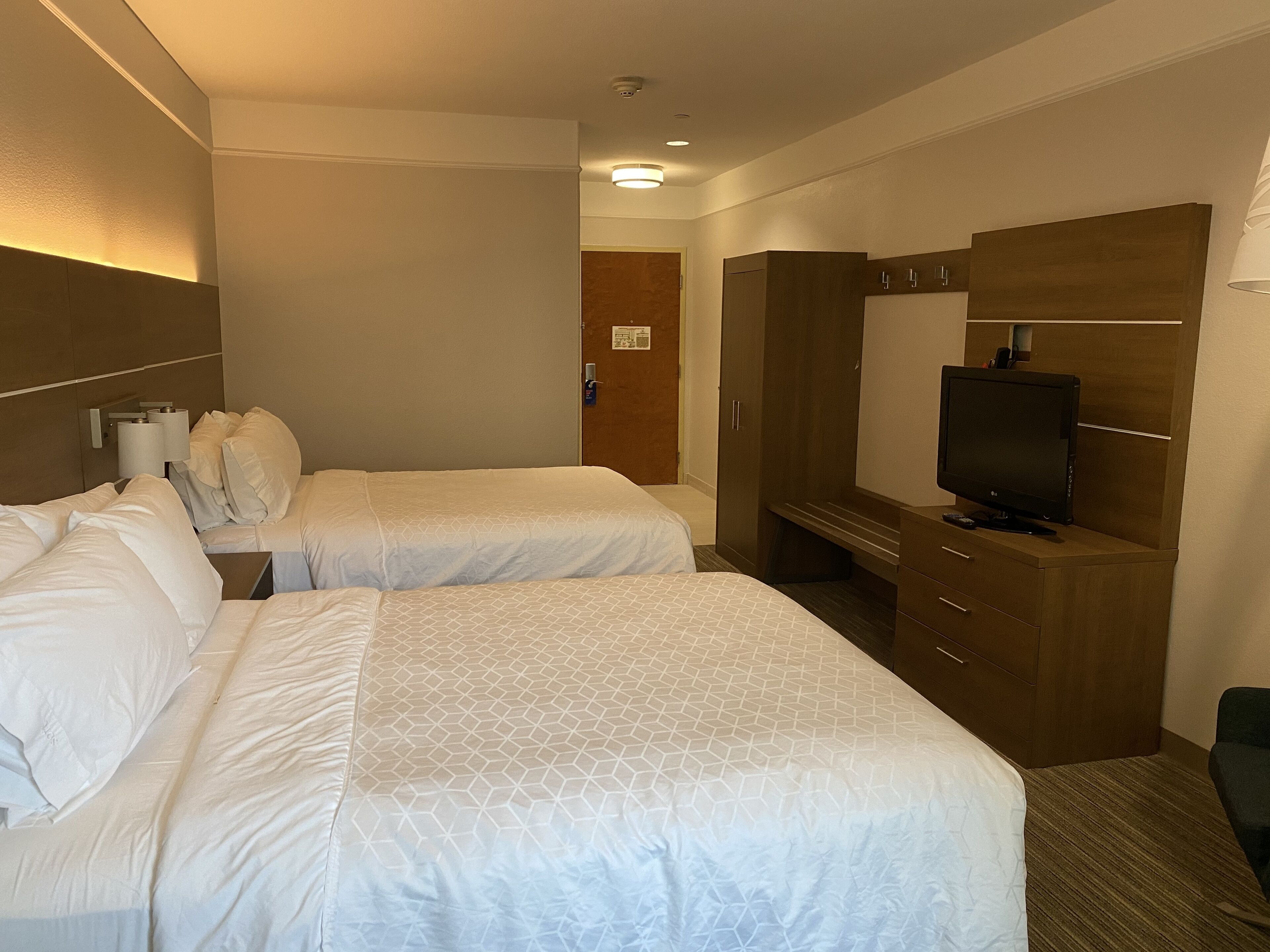 A hotel room with two beds, a TV, and a wardrobe.
