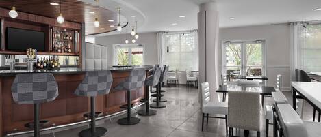 A modern bar area with a counter, bar stools, and a television screen.