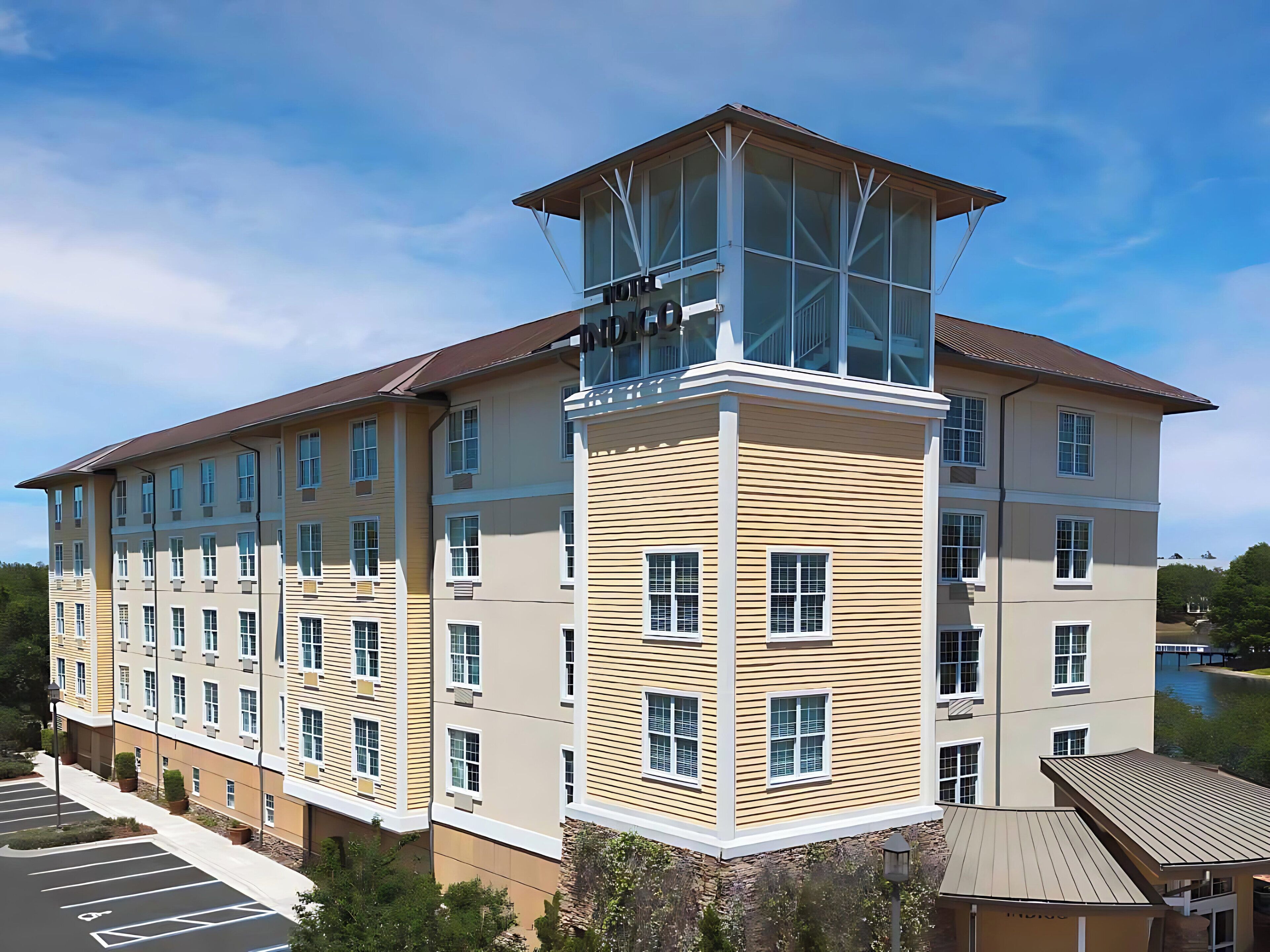 A multi-story hotel with a central tower, large windows, and a parking lot.
