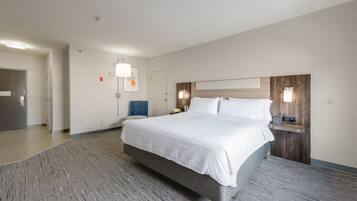 Quarto de hotel com cama grande, mesa de cabeceira e luminária na parede.