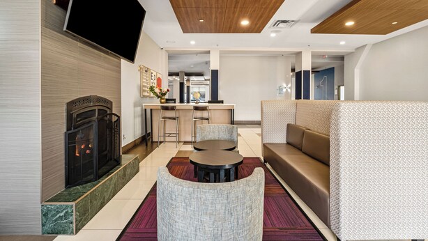 A modern hotel lobby with a fireplace, seating area, and a bar. - Holiday Inn Express Hotel & Suites Edmonton South by IHG (Edmonton)