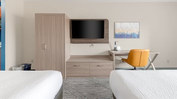 A hotel room with two beds, a desk with a chair, a TV mounted on the wall, and a painting above the desk.