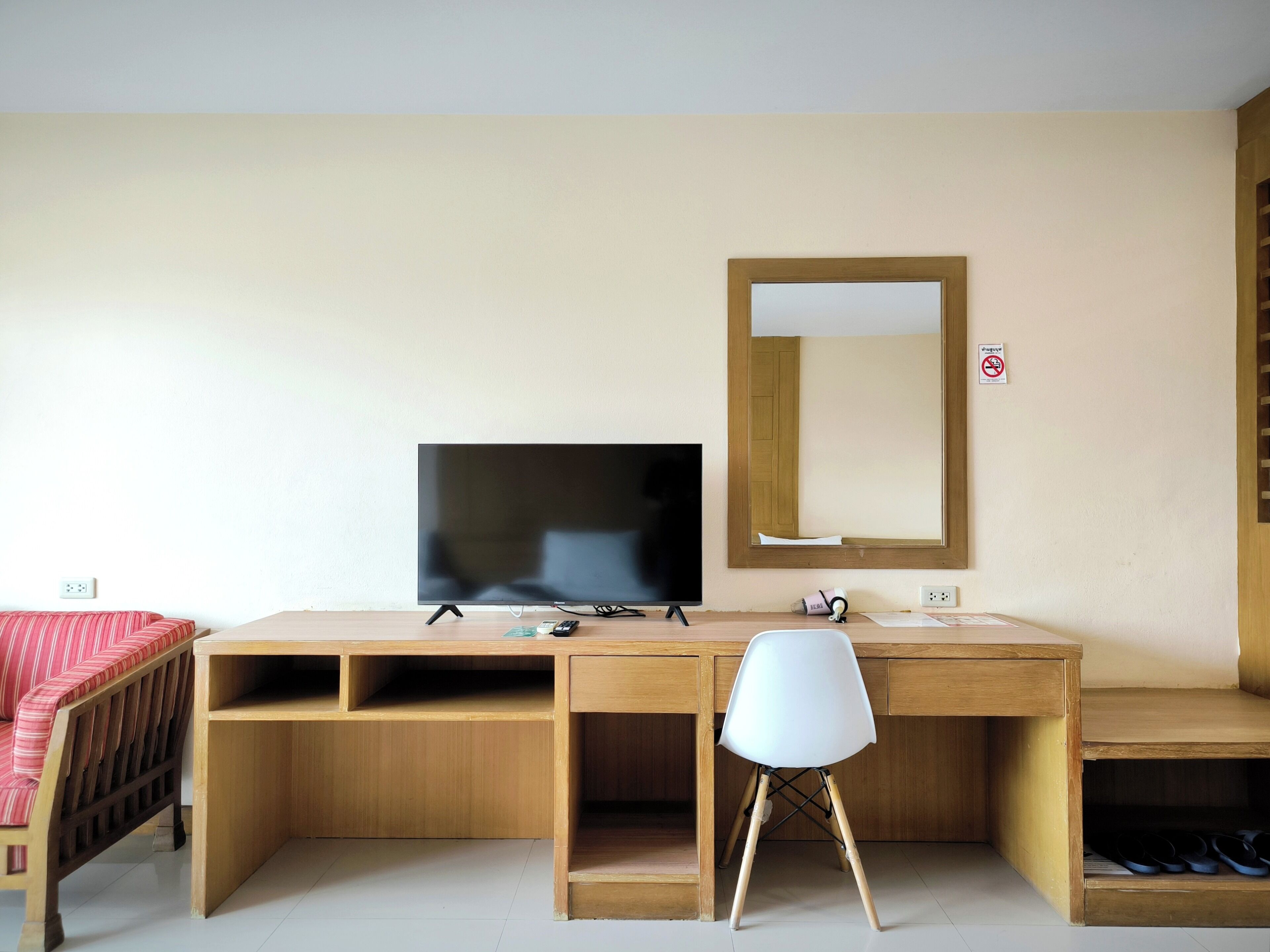 Een houten bureau met een televisie, een witte stoel en een spiegel.