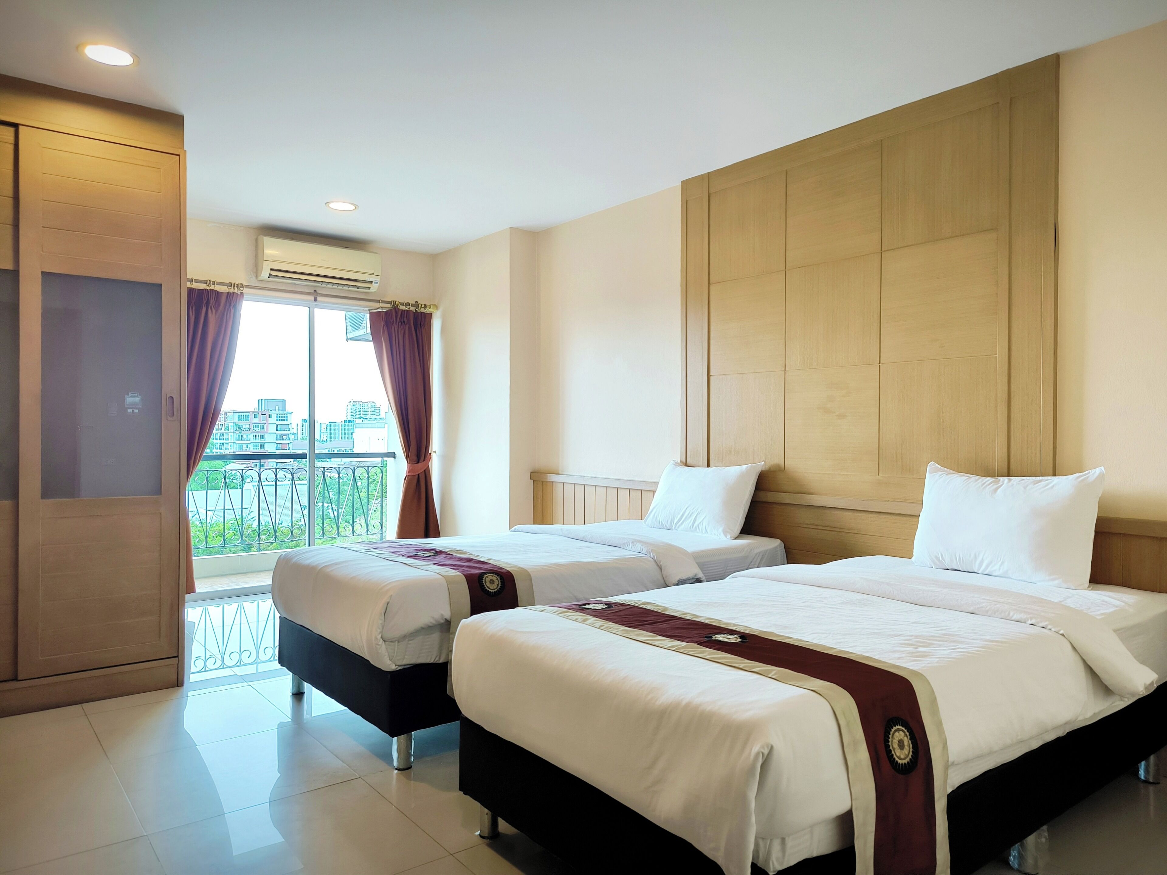 A hotel room with two beds, a balcony with a view, and a wooden headboard.
