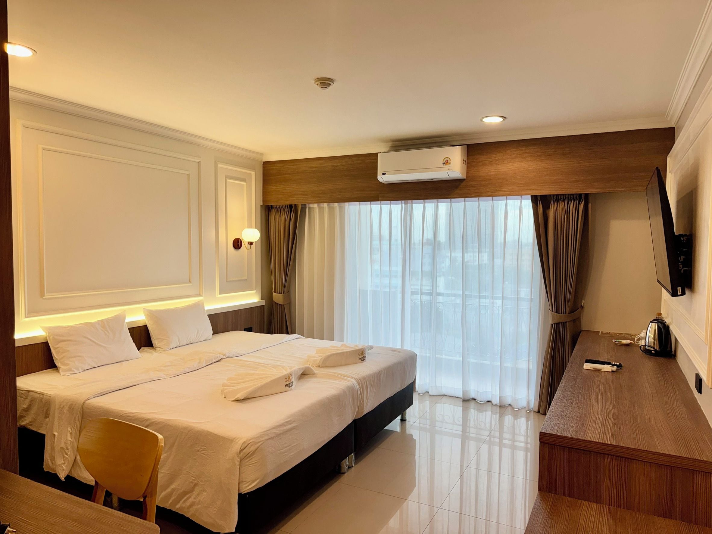 Une chambre d’hôtel équipée d’un lit, de tables de chevet, d’un bureau, d’une chaise, d’un climatiseur et d’un téléviseur.