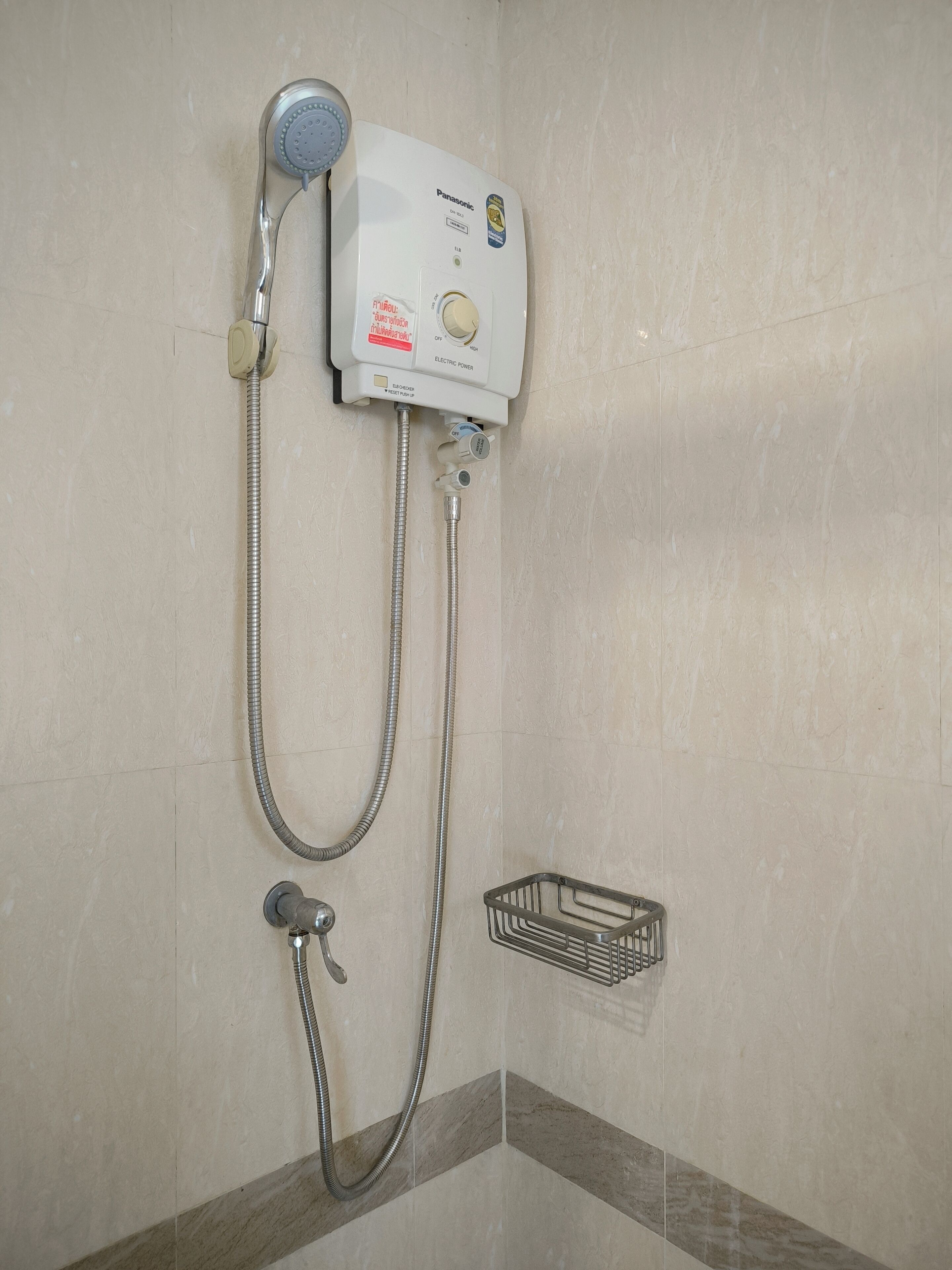A bathroom with a wall-mounted shower unit, a handheld showerhead, and a metal shower tray.