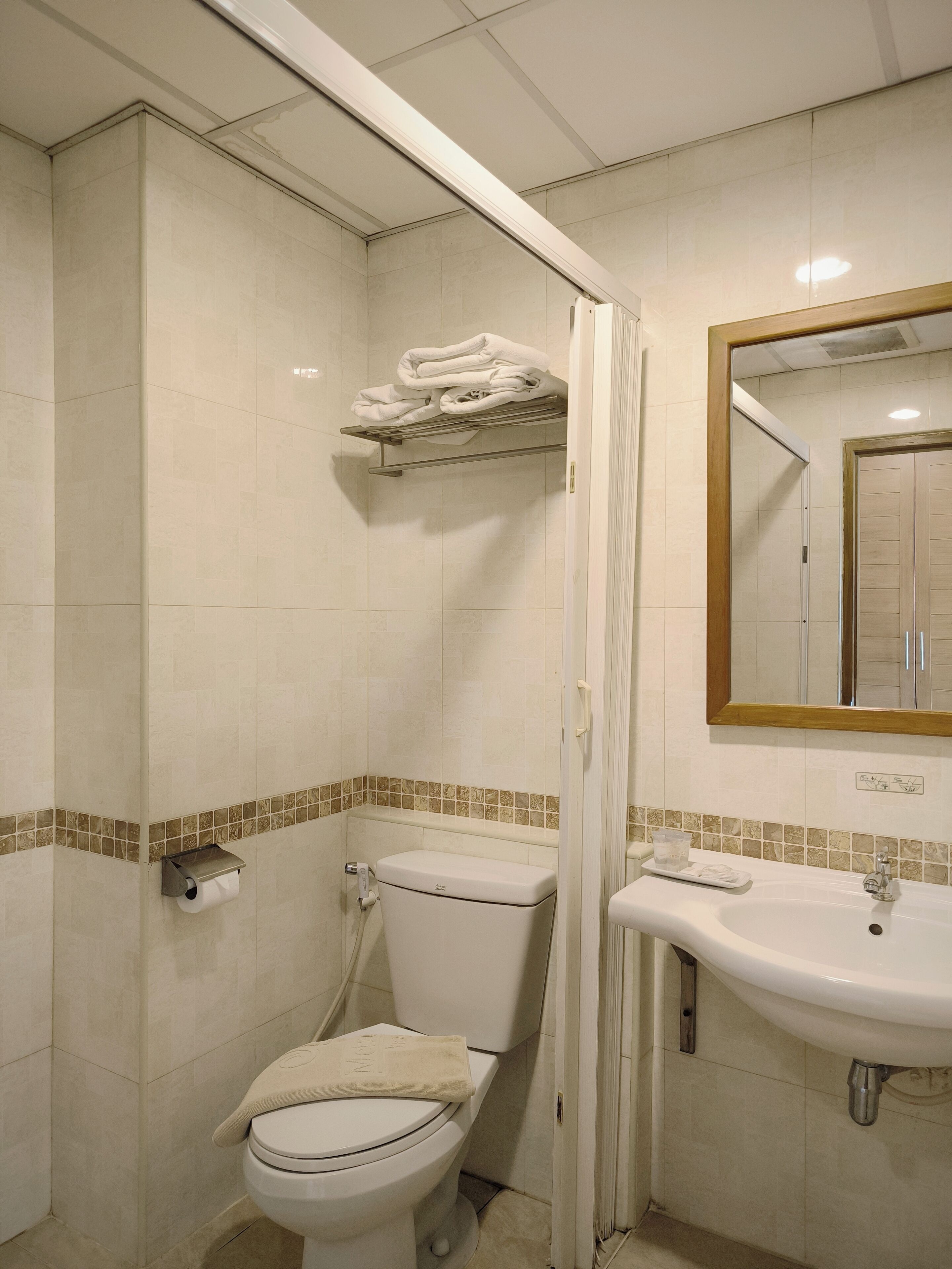 Un baño con inodoro, lavamanos y toallero.