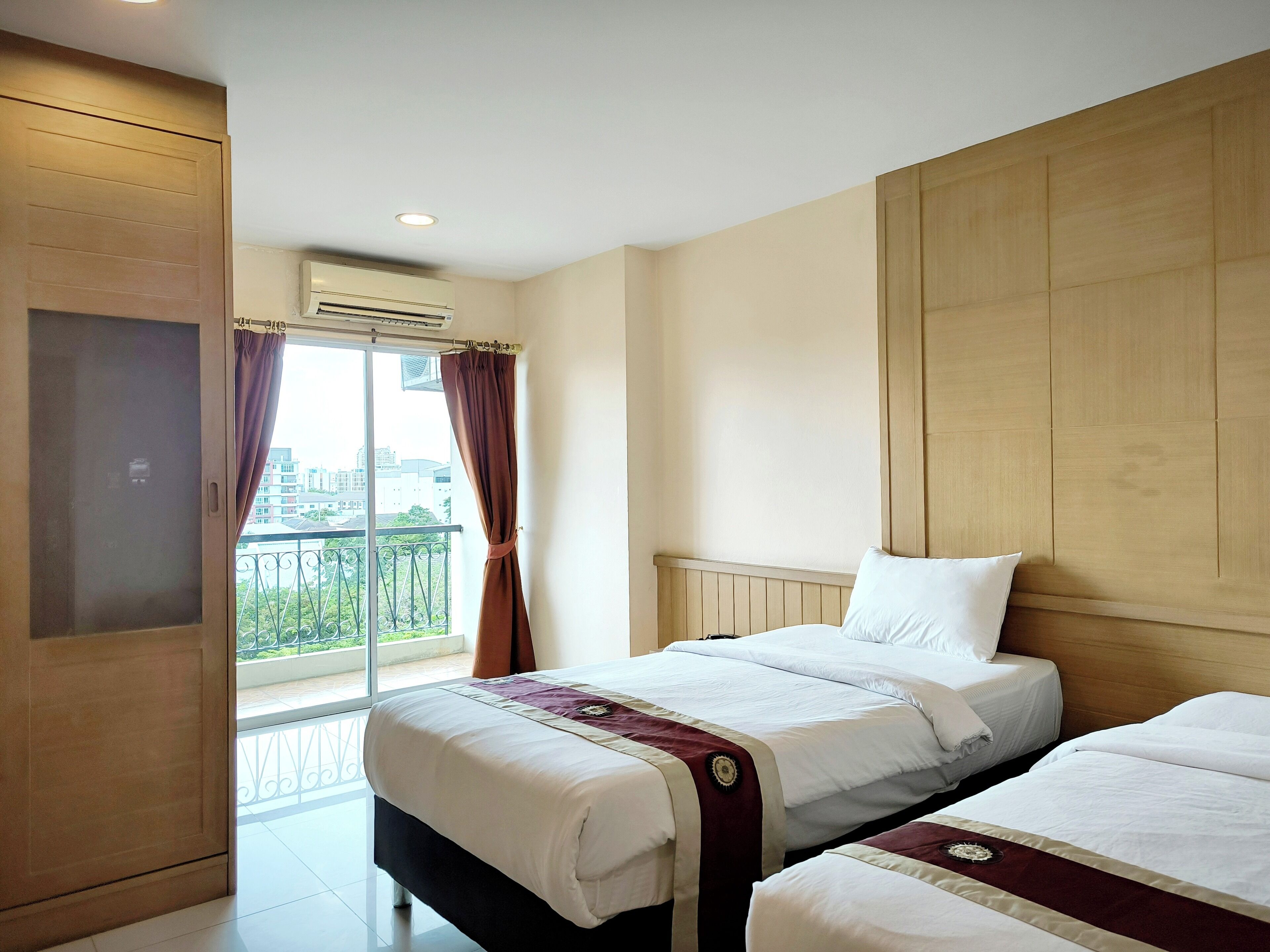 Een hotelkamer met twee bedden, een balkon en uitzicht, en een airconditioning.