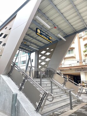 Una escalera moderna con barandales de metal y un letrero que indica una estación de metro.