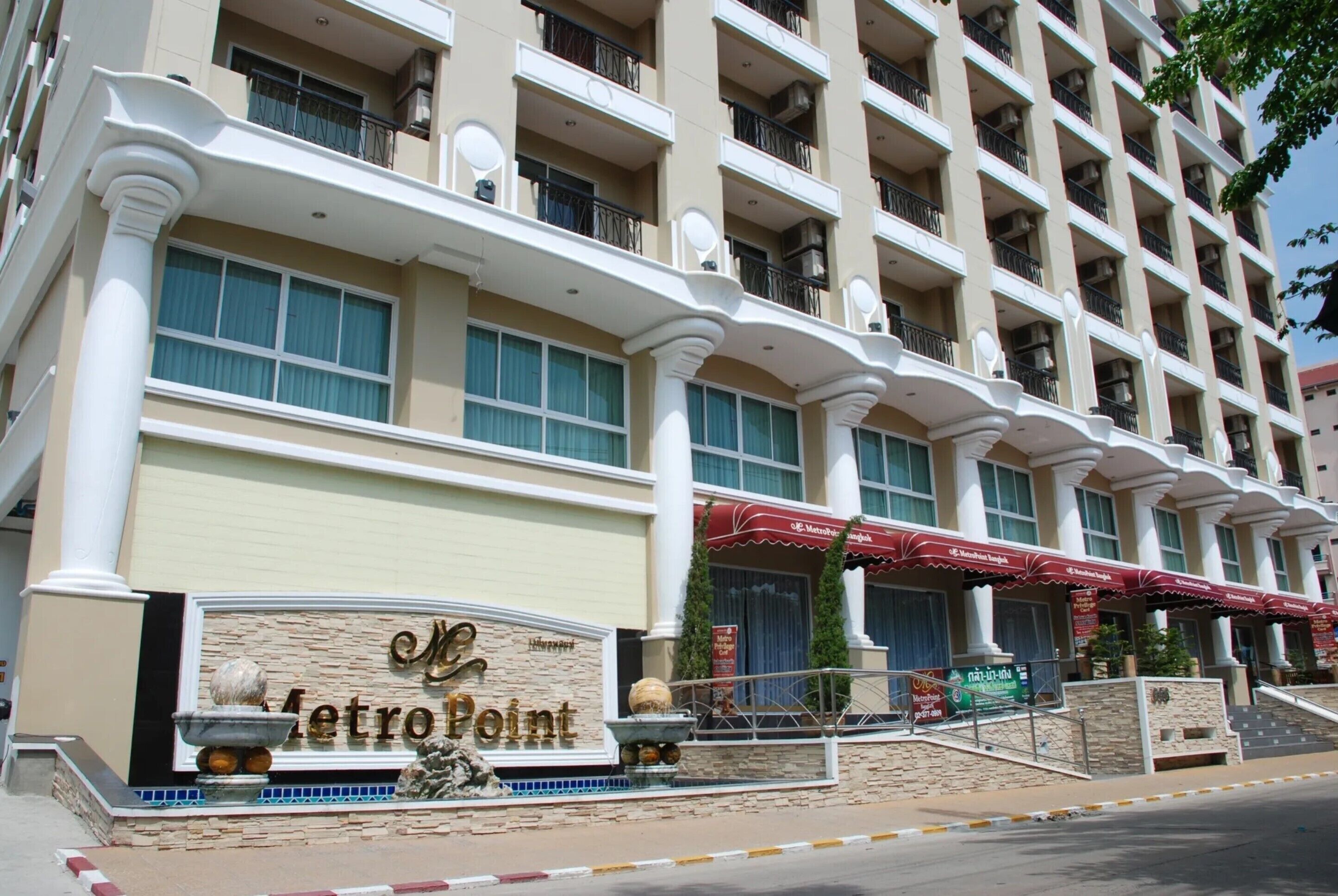 Um hotel com vários andares, entrada destacada, varandas e uma placa com o nome 'MetroPoint'.