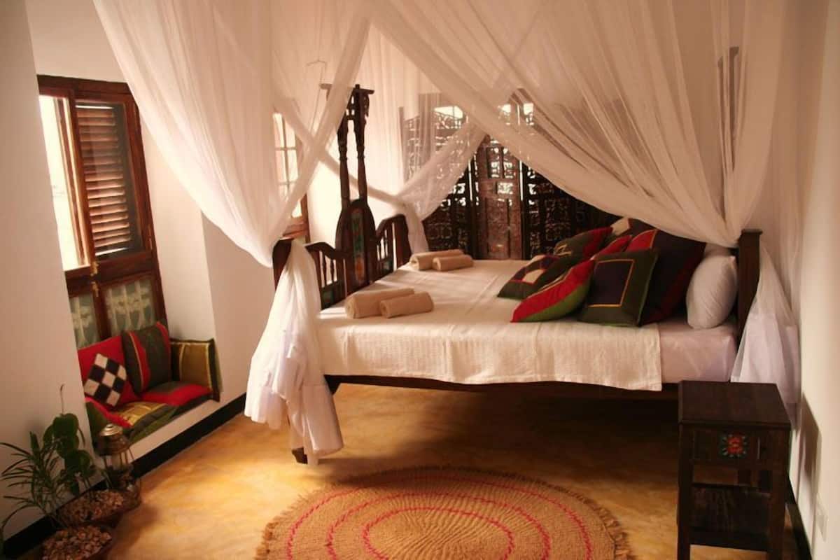 A bed with a canopy, a wooden headboard, and a bedside table.