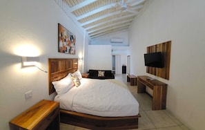 A bedroom with a wooden bed, a nightstand, a TV mounted on the wall, and a ceiling fan.