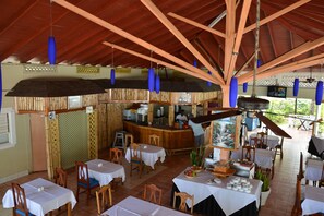 A restaurant with wooden tables and chairs, a bar area, and a view of the outdoors.