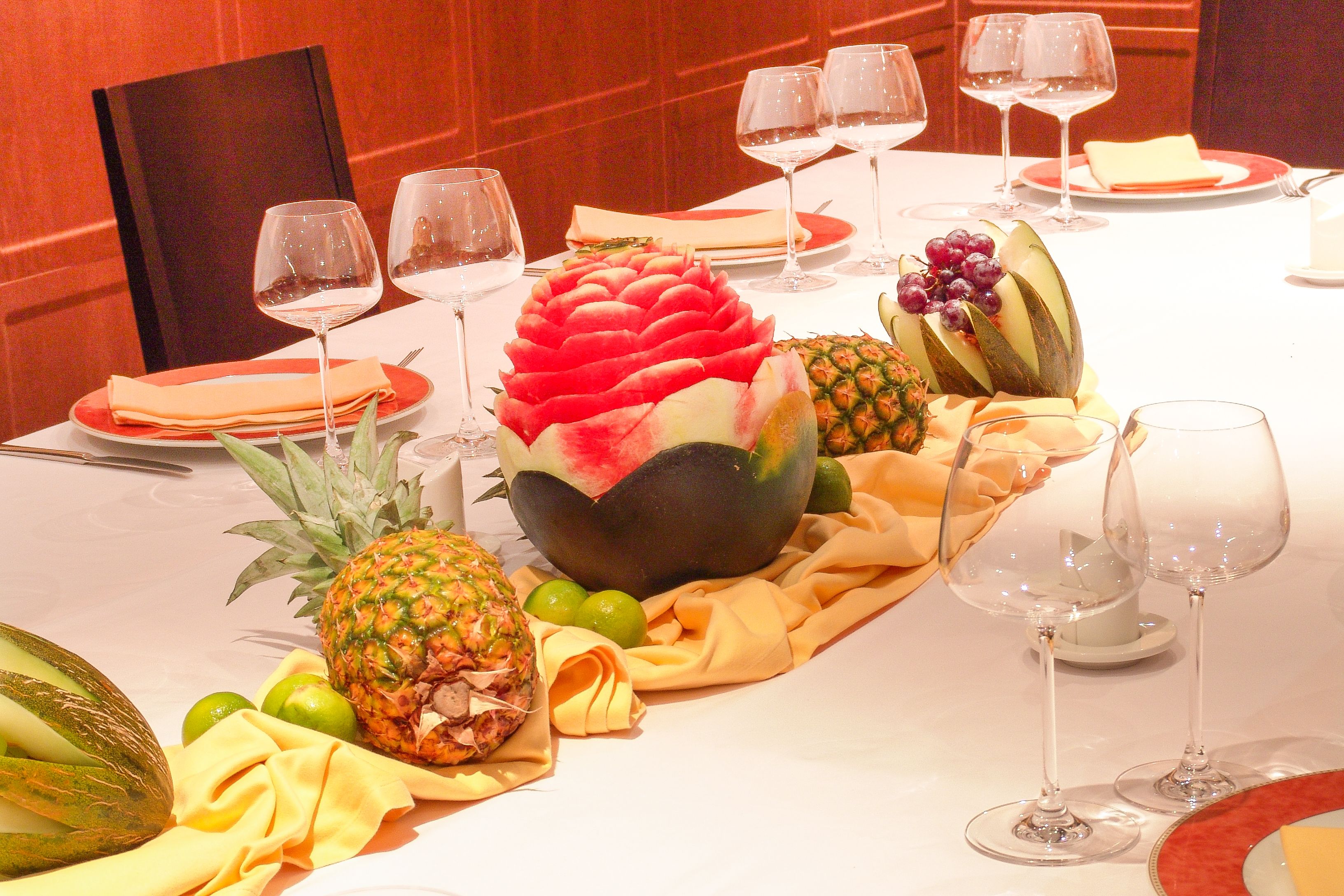 A table set for a meal with various fruits, wine glasses, and plates.