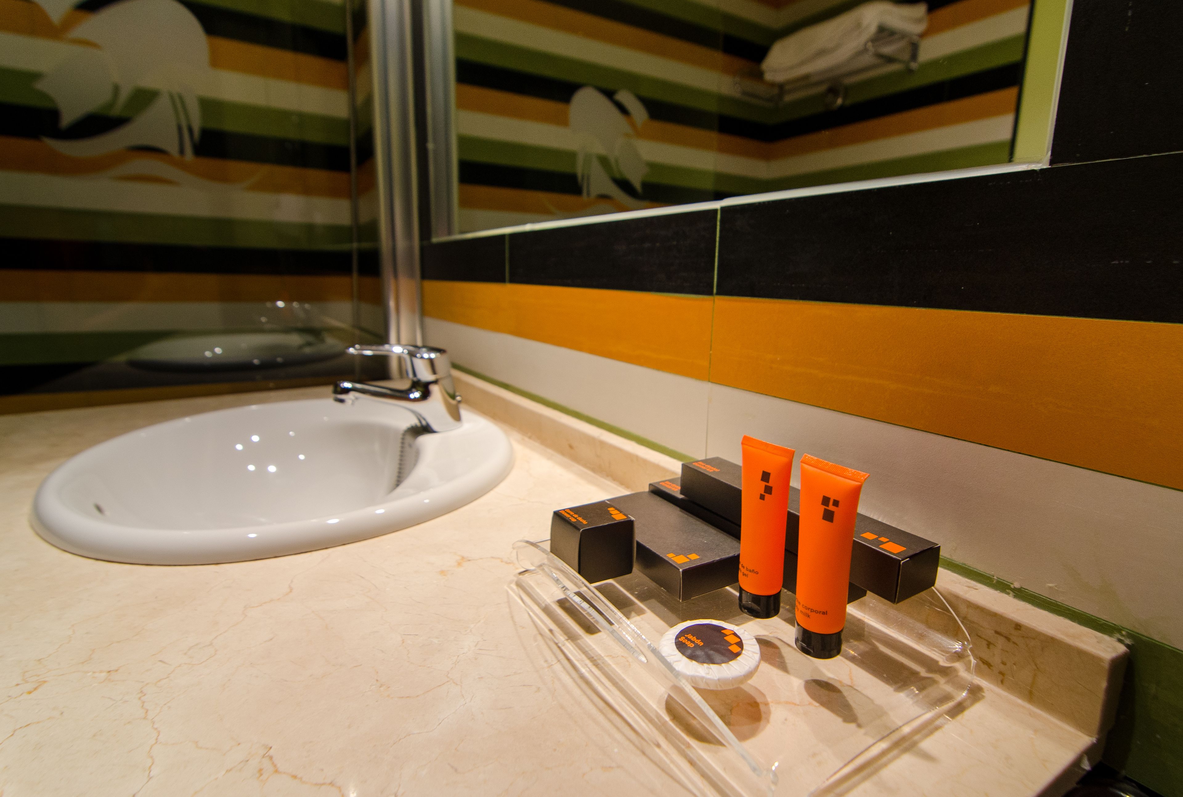 A bathroom with a white sink, a glass shower enclosure, and toiletries on a tray.