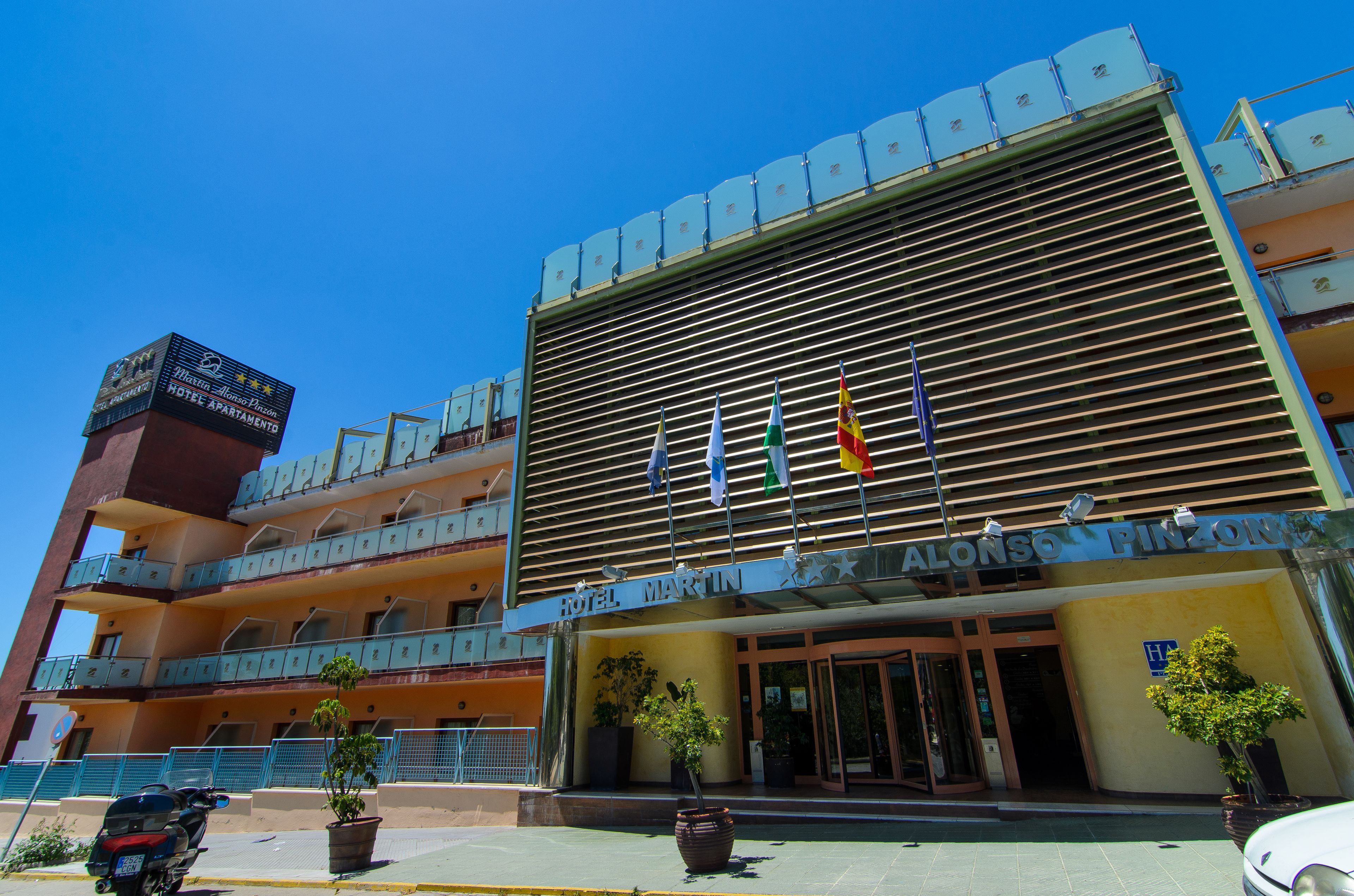 Een hotel met een moderne gevel, meerdere balkons en een bord waarop staat 'Alonso Finances Hotel'.