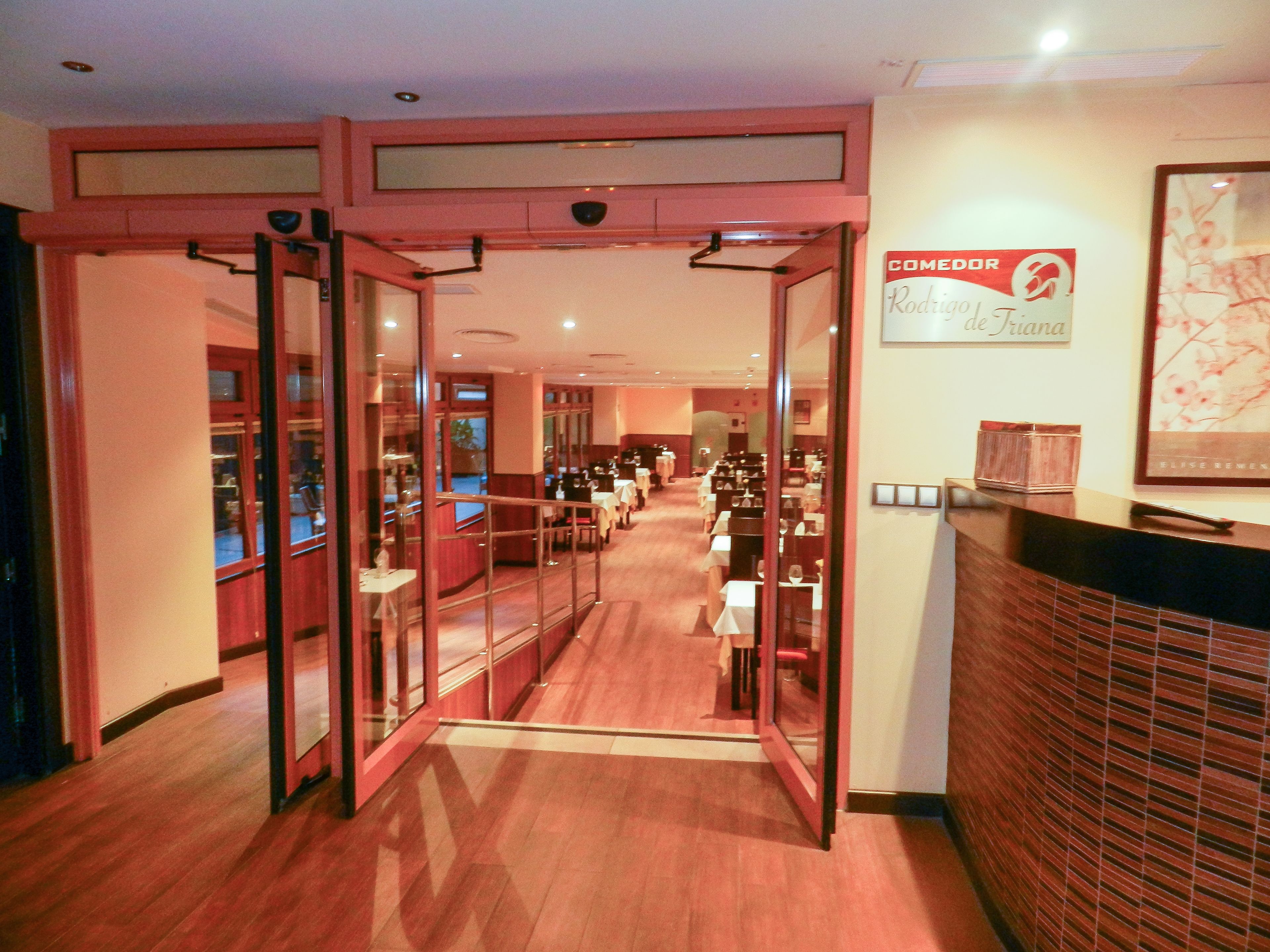 A hotel lobby with a glass partition leading to a dining area.