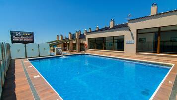 A swimming pool with a wooden deck, a lifebuoy, and a sign for the Martin Alonso Pinzón Hotel & Apartment.