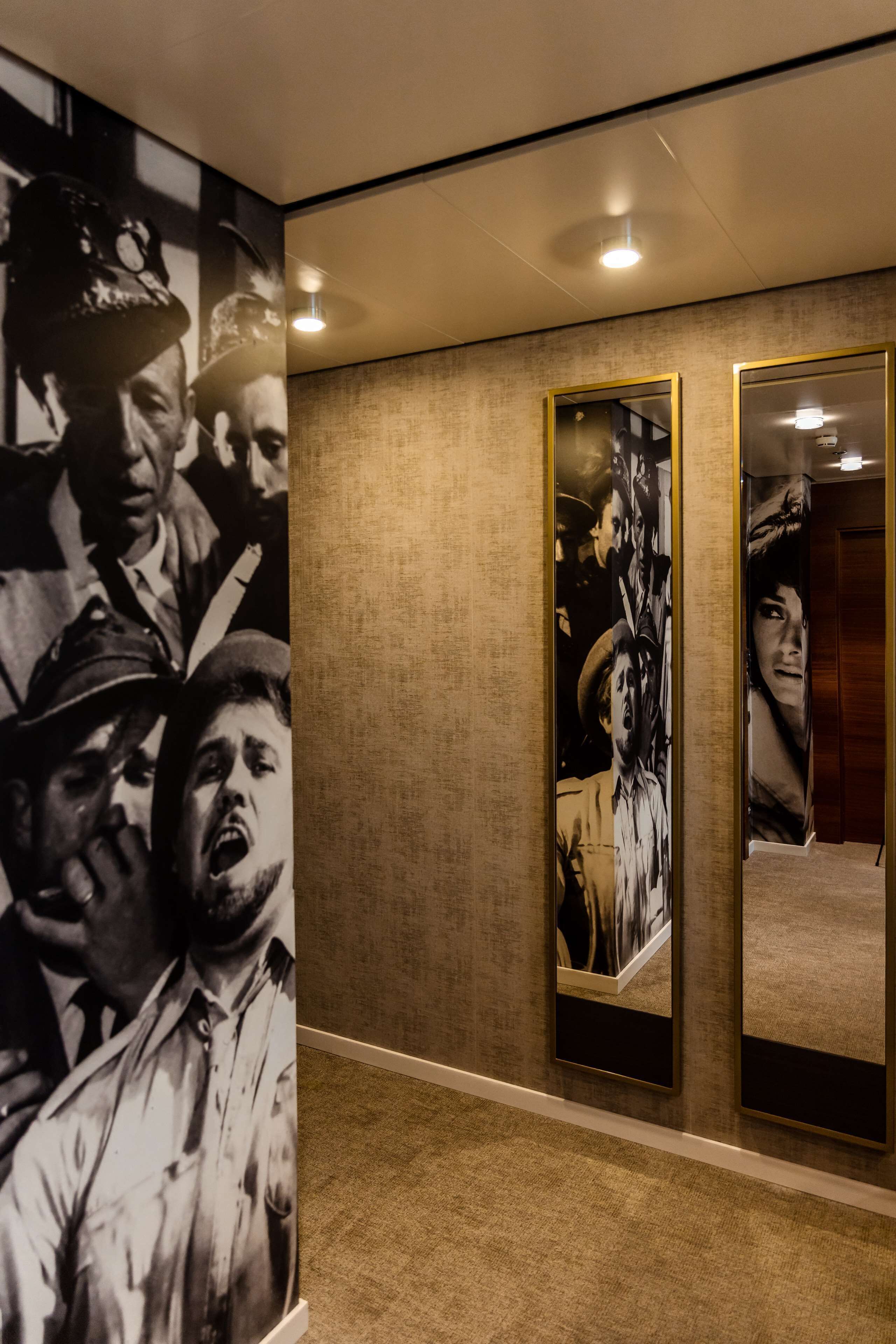 A hallway with a textured wall, a large black-and-white photograph, and two framed mirrors.