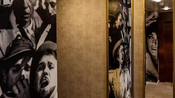 Un pasillo con una pared con textura, una fotografía grande en blanco y negro y dos espejos enmarcados.