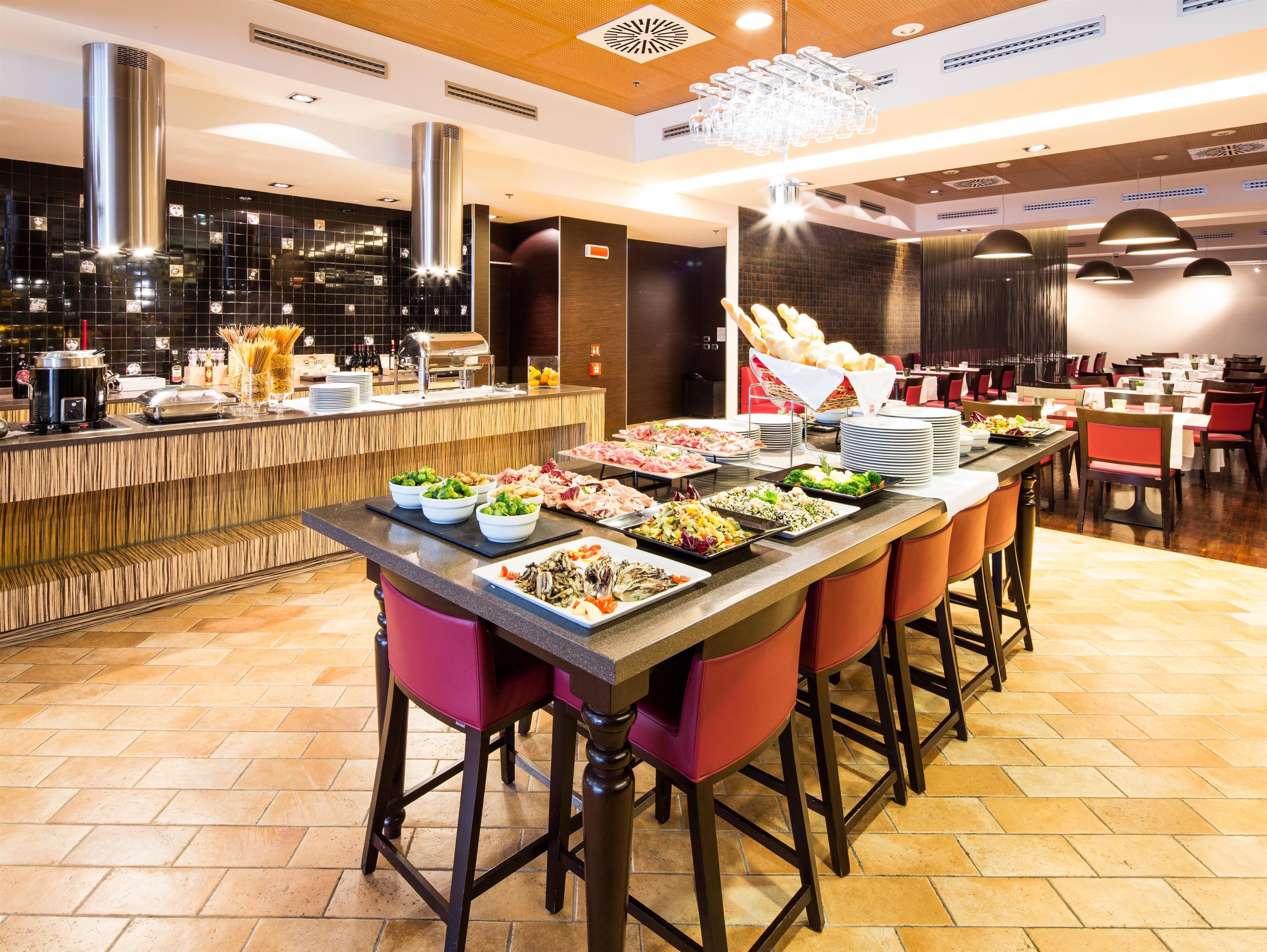 Montaje tipo bufé con diferentes opciones de comida, una zona de bar y disposición de mesas.