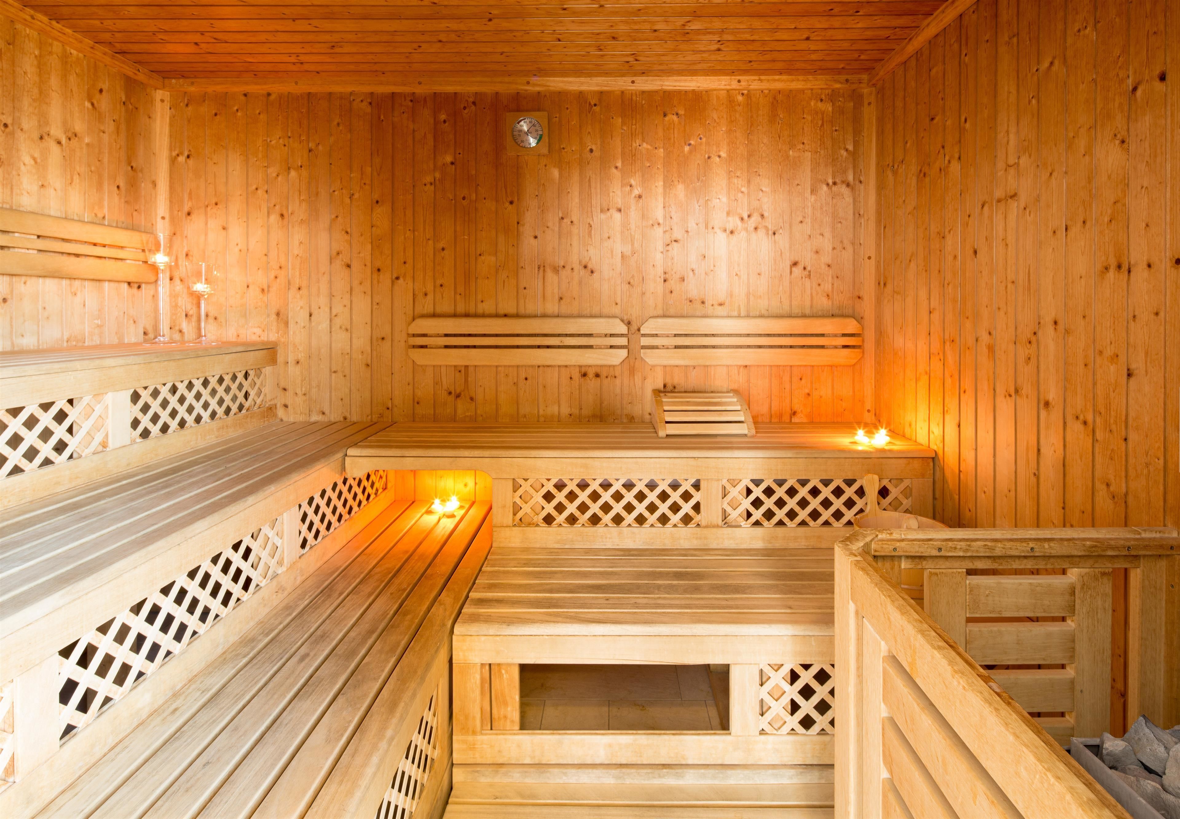 Eine Sauna mit Holzbänken und Gitterabtrennungen, einer Holzbeschichtung und einer sichtbaren Leuchte.